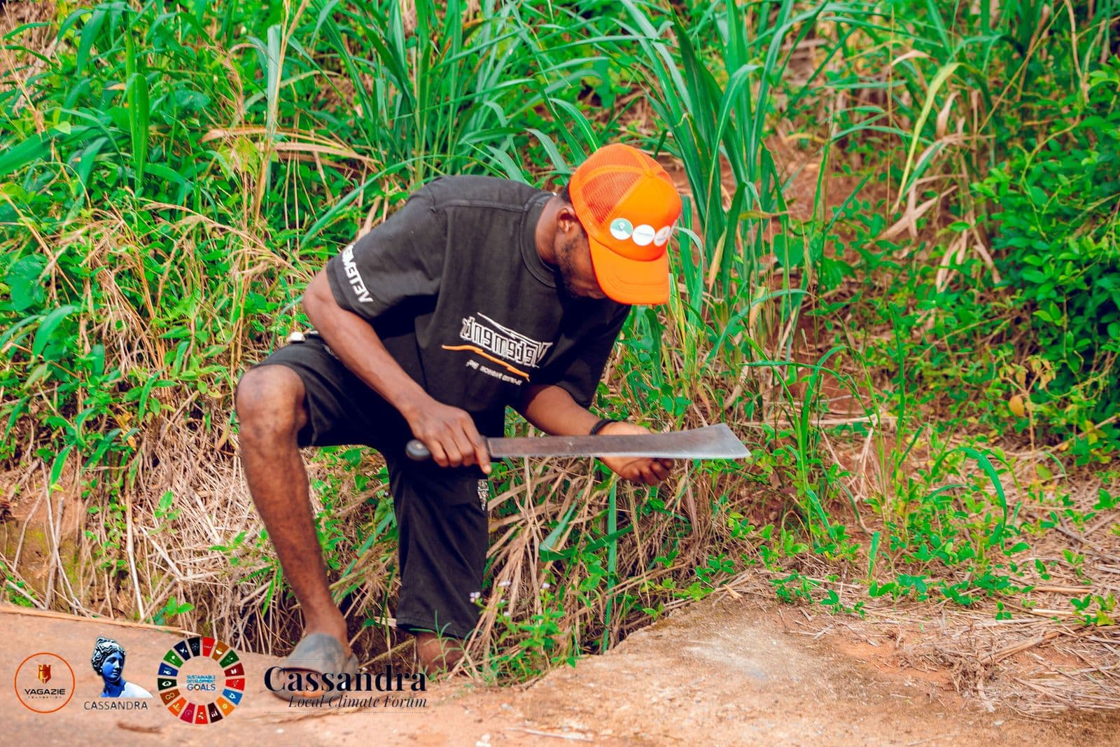 A volunteer cuts back vegetation with a machete to clear a channel
