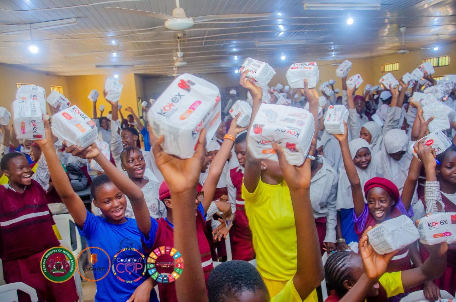 Girls hold up packs of menstrual products