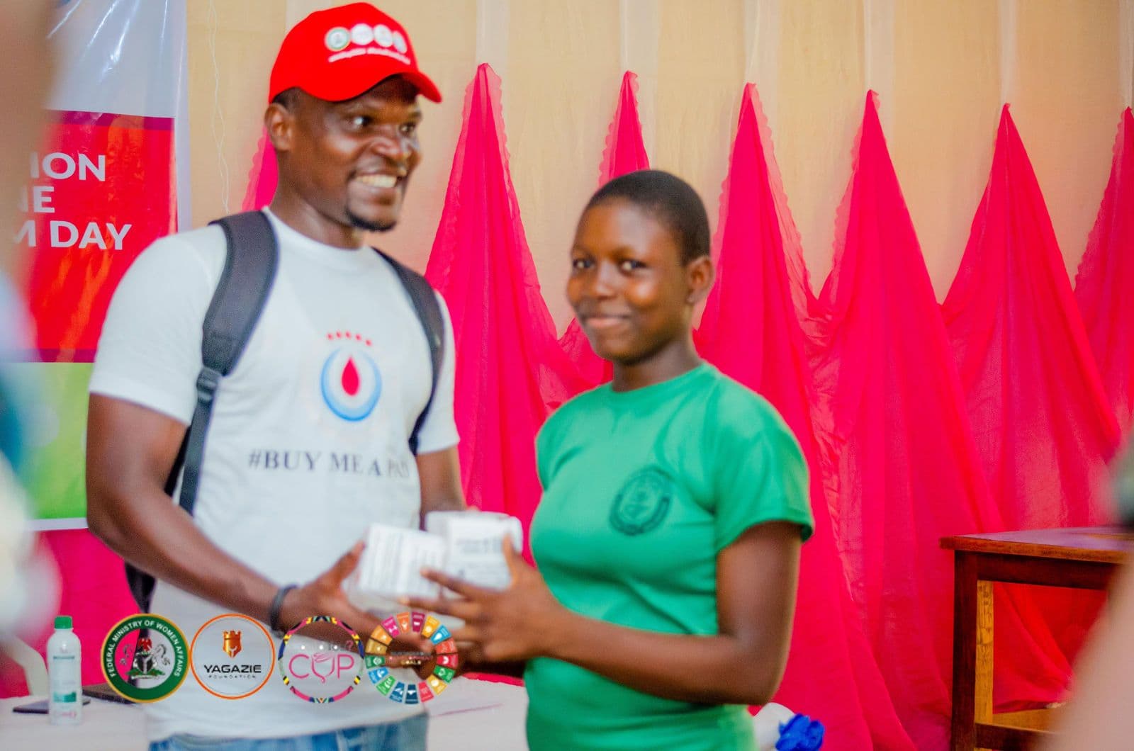 A volunteer hands a student a pack of menstrual products
