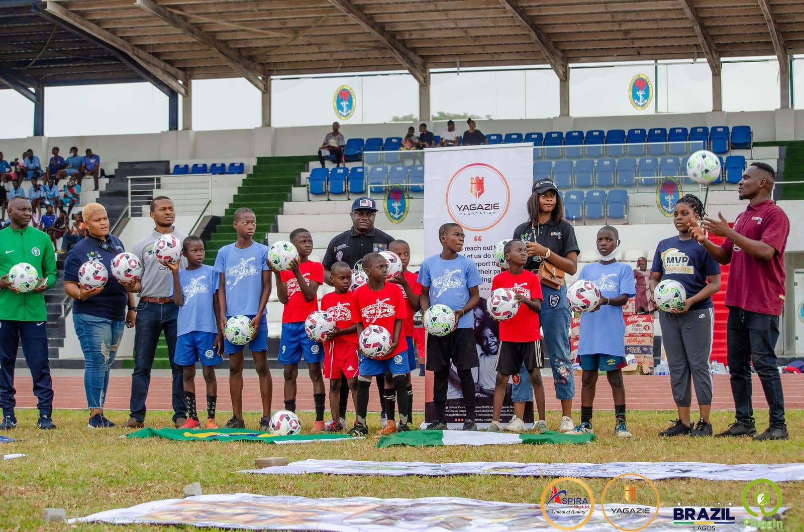 Young participants and mentors pose together at the YES Camp with Nigerian and Brazilian flags behind them