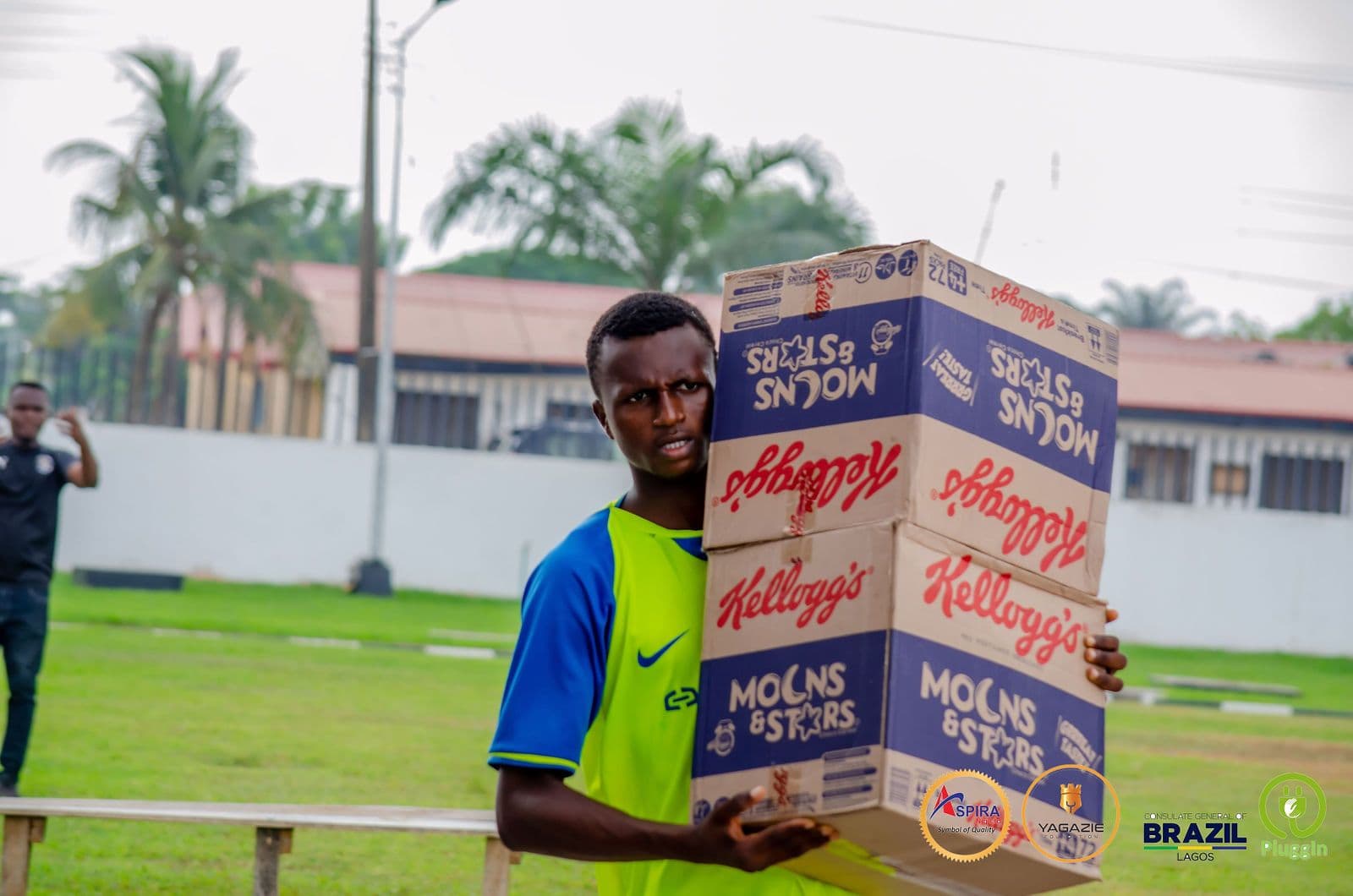 A young participant carries a box of cereal donated for the camp